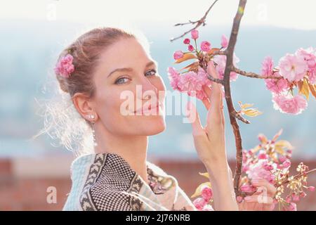 Junge weiße, weiche Frau, die im Frühling Kirschblüte hält Stockfoto