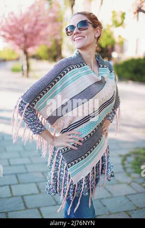 Glückliche junge fröhlich Hipster 30s Frau in Poncho toothy Lächeln im Park Stockfoto