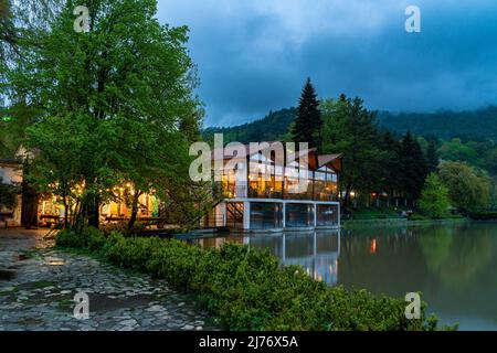 Dilijan, Armenien - 6. Mai 2022 - Blick auf den wunderschönen künstlichen See von Dilijan an einem späten Abend mit bewölktem Himmel Hintergrund und Cafe #2 Gebäude vorbei Stockfoto