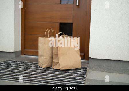 Papiertüten voller frischer Lebensmittel auf der Veranda vor dem Haus. Stockfoto