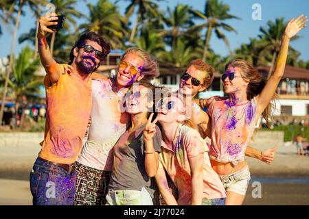 Fröhliche Menschen in farbenfroher holi-Farbe spielen am Strand auf festlichen in Goa Beach India Stockfoto