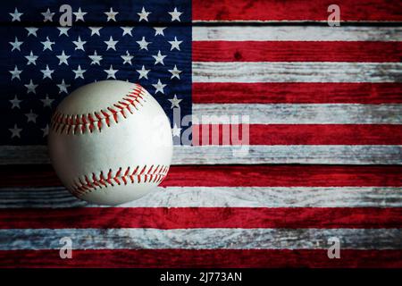 Leder-Baseballspiel auf rustikalem Holzhintergrund mit US-Flagge mit Kopierraum bemalt. Stockfoto