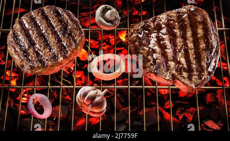 Zwei gegrillte Rindersteaks auf dem grill rosten über heiße Kohlen. Draufsicht. Stockfoto