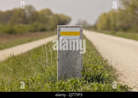 Weißer und gelber Wandermarker auf einem Granitpfosten Stockfoto