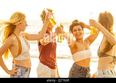indische hispanische Frau im Fokus hält Flasche mit Limonade oder Bier und klickt mit Freunden Stockfoto