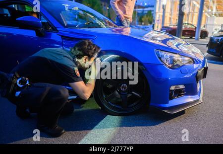 06. Mai 2022, Niedersachsen, Hannover: Ein Polizist überprüft ein getuntes Fahrzeug im Expo Park. Am Freitagabend trafen sich wieder Hunderte von Autotunern und Autofans auf dem ehemaligen Expo-Gelände in Hannover. Die Polizei von Hannover kontrollierte zahlreiche Fahrzeuge auf den Zufahrtsstraßen. Foto: Julian Stratenschulte/dpa Stockfoto