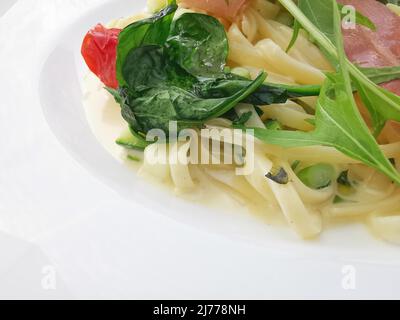 Blick auf Gourmet-Nudelgericht mit parmaschinken, Spinat und Rucola Stockfoto