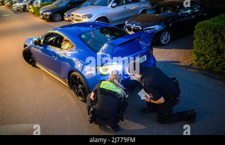 06. Mai 2022, Niedersachsen, Hannover: Polizeibeamte überprüfen im Expo Park ein getuntes Fahrzeug. Am Freitagabend trafen sich wieder Hunderte von Autotunern und Autofans auf dem ehemaligen Expo-Gelände in Hannover. Die Polizei von Hannover kontrollierte zahlreiche Fahrzeuge auf den Zufahrtsstraßen. Foto: Julian Stratenschulte/dpa Stockfoto