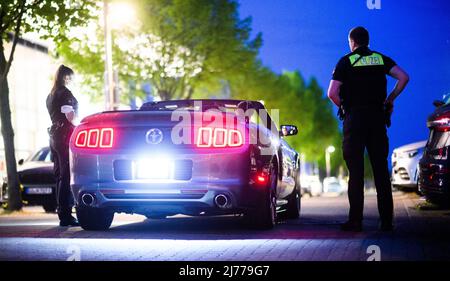 06. Mai 2022, Niedersachsen, Hannover: Polizeibeamte überprüfen im Expo Park ein getuntes Fahrzeug. Am Freitagabend trafen sich wieder Hunderte von Autotunern und Autofans auf dem ehemaligen Expo-Gelände in Hannover. Die Polizei von Hannover kontrollierte zahlreiche Fahrzeuge auf den Zufahrtsstraßen. Foto: Julian Stratenschulte/dpa Stockfoto