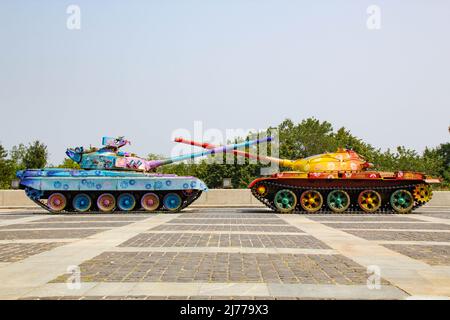 Die Tanks sind in leuchtenden Farben lackiert. Militärfahrzeuge sind mit Blumenmustern bemalt. Panzer mit gekreuzten Fässern. Anti-Kriegs-Konzept Stockfoto