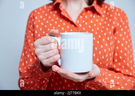 Blaue und weiße Tasse in den Händen einer Nahaufnahme. Modell. Speicherplatz kopieren Stockfoto