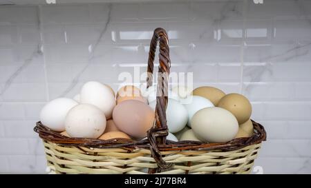 Freilandeier in verschiedenen Farben befinden sich in einem Korb. Stockfoto