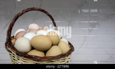 Freilandeier in verschiedenen Farben befinden sich in einem Korb. Stockfoto