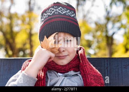 Kind mit einem Urlaub in der Hand, mit Wollmütze und Schal. Fallen Stockfoto
