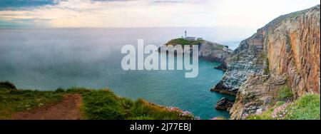 Dramatische Klippen und South Stack Lighthouse, Holyhead, durch den Morgennebel, Angelsey, Nordwales Stockfoto