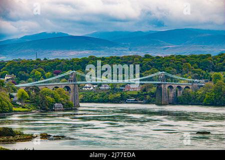 Die Menai-Hängebrücke über den Menai, die von Thomas Telford entworfen wurde, um das Festland mit der Insel Anglesey in Nordwales zu verbinden Stockfoto