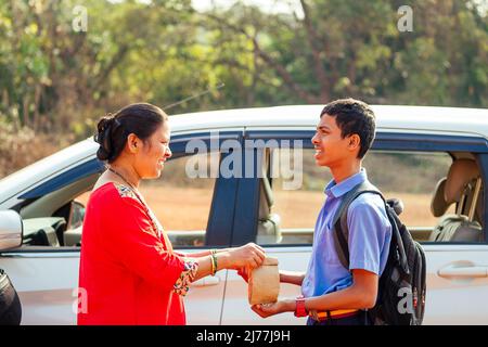 indische Familie, die Jungen zur Schule vor den Haustüren fährt Stockfoto