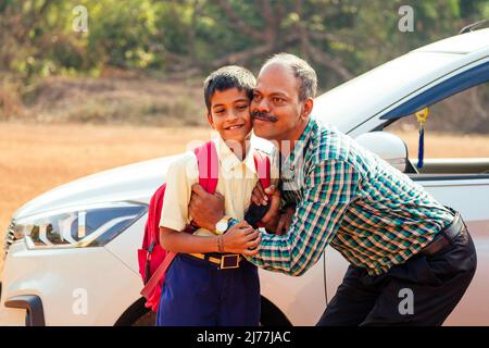 indische Familie, die Jungen zur Schule vor den Haustüren fährt Stockfoto