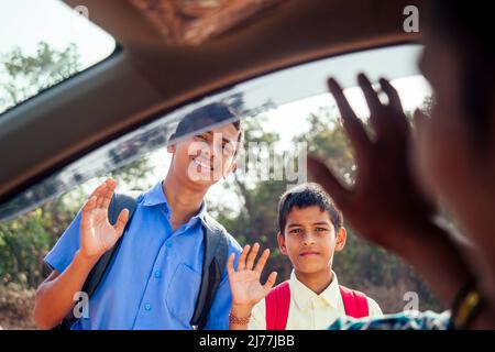 indische Familie, die Jungen zur Schule vor den Haustüren fährt Stockfoto