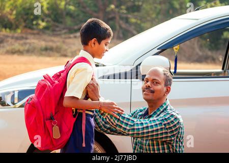 indische Familie, die Jungen zur Schule vor den Haustüren fährt Stockfoto