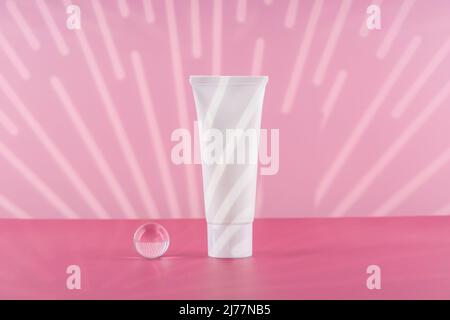 Unbranded kosmetische Creme weißen Plastikröhrchen Mockup auf rosa Hintergrund mit stilvollen Requisiten. Leere Körper- und Gesundheitspflege-Beauty-Produktverpackung Stockfoto