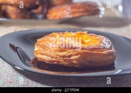 Süßes Blätterteig gefüllt mit Aprikose und Pfirsich auf einer schwarzen Schale mit weichem Licht. Stockfoto