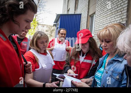 Velievaa (22), Alex und ihre Kollegen helfen einer Frau, ein Antragsformular für Medikamente auszufüllen, die sie in Kharkiv brauchte. Trotz des ständigen Beschusses von russischen Truppen, die die Stadt Charkow umzingeln, setzten Mediziner und Freiwillige des Roten Kreuzes ihre Arbeit 24/7 fort, um Leben zu retten und Menschen in Not zu helfen. (Foto von Alex Chan Tsz Yuk / SOPA Images/Sipa USA) Stockfoto