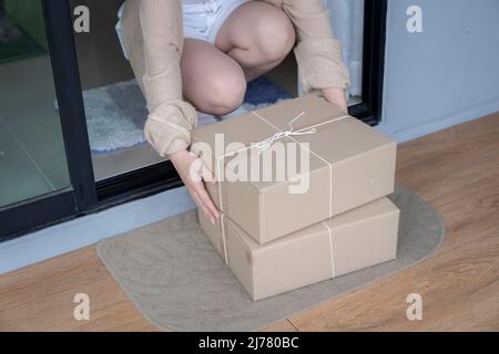 Nahaufnahme Liefermann in roter Uniformpackung, während die Kundin die Unterschrift auf Papier unterzeichnet und Dokumente erhält. Stockfoto