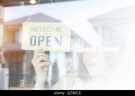 Asiatische Frau Eigentümer Laden öffnen Schild durch die Tür Glas und bereit zum Service. Stockfoto