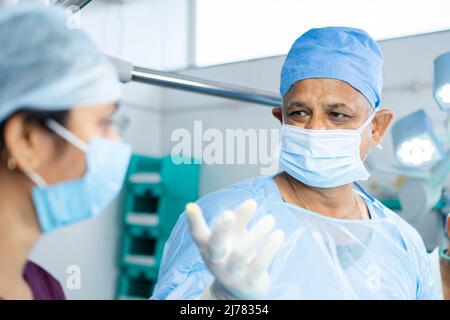 Nahaufnahme des Chirurgen, der mit einer Operation beschäftigt ist, mit einem Support-Personal oder einem Arzt im OP-Theater - Konzept des professionellen Berufs Stockfoto