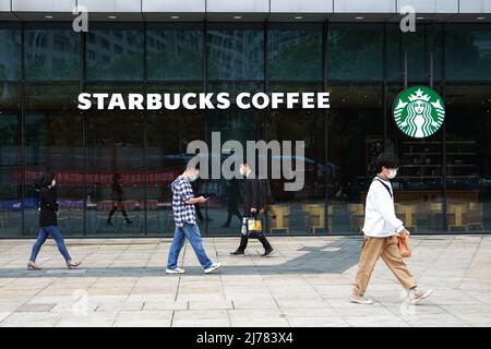 29. April 2022, Changzhou, Jiangsu, China: Fußgänger mit Gesichtsmasken gehen am Eingang eines Starbucks-Cafés in Changzhou vorbei. (Bild: © Sheldon Cooper/SOPA Images via ZUMA Press Wire) Stockfoto