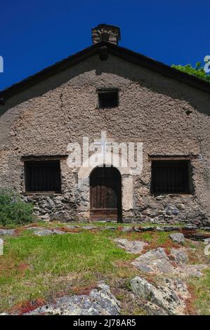 Schutt und Raufuß ragen an der rustikalen Westfront der Dorfkirche Sant Pere del Serrat in El Serrat im Ordino-Tal, Andorra, die Ende 1500s hoch in den östlichen Pyrenäen gegründet wurde. Stockfoto