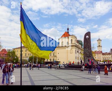 Der Krieg in der Ukraine. Ukrainische Flagge vor dem Hintergrund des Stadtrats von Lemberg und des Denkmals für Taras Schewtschenko Stockfoto