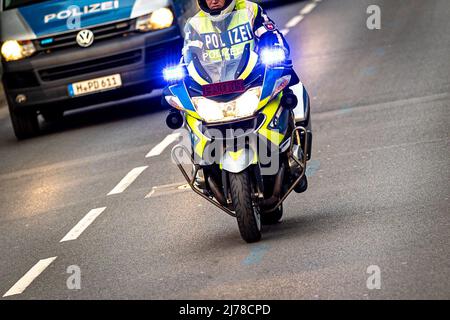 04. Mai 2022, Niedersachsen, Hannover: Ein Polizeibeamter fährt mit einem BMW Polizeimotorrad durch eine Straße mit blauer Ampel. Foto: Moritz Frankenberg/dpa Stockfoto