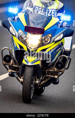 04. Mai 2022, Niedersachsen, Hannover: Ein Polizeibeamter fährt mit einem BMW Polizeimotorrad durch eine Straße mit blauer Ampel. Foto: Moritz Frankenberg/dpa Stockfoto