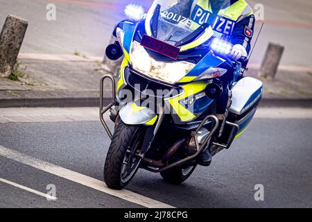 04. Mai 2022, Niedersachsen, Hannover: Ein Polizeibeamter fährt mit einem BMW Polizeimotorrad durch eine Straße mit blauer Ampel. Foto: Moritz Frankenberg/dpa Stockfoto