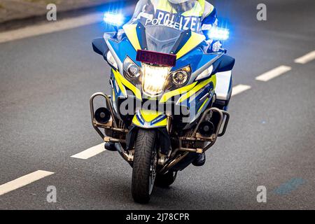 04. Mai 2022, Niedersachsen, Hannover: Ein Polizeibeamter fährt mit einem BMW Polizeimotorrad durch eine Straße mit blauer Ampel. Foto: Moritz Frankenberg/dpa Stockfoto