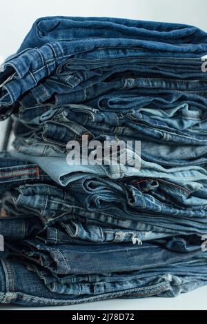 Der Stapel des Stapels der alten Jeans verschiedene Schattierungen der blauen Jeans. Denim-Jeans-Struktur. Denim-Hintergrundtextur für Design. Denim-Struktur in Canvas. Blauer Denim Stockfoto