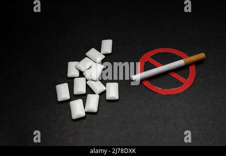 Nikotinersatzgummi neben einer Zigarette mit dem verbotenen Zeichen, Konzept des Rauchens Stockfoto
