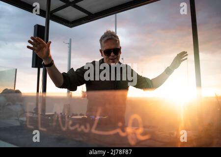 Deejay Mischung im Freien mit Gegensonnenlicht - Porträt von Disc Jockey spielen Disco oder tiefe Musik für die Menschen auf Strandparty bei Sonnenuntergang - Spaß und, Sommer, Stockfoto