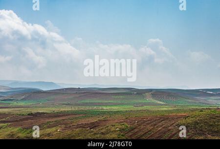 Am Berghang landwirtschaftlich bewirtschaftete Felder mit hellblauem Himmel am Morgen aus flachem Winkel Stockfoto