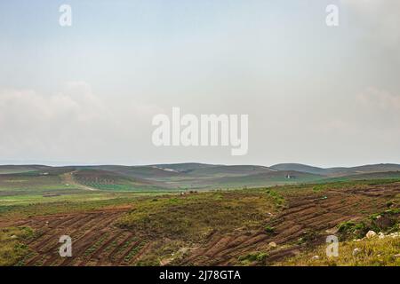 Am Berghang landwirtschaftlich bewirtschaftete Felder mit hellblauem Himmel am Morgen aus flachem Winkel Stockfoto