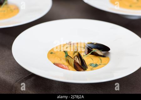 Karotten-Sahnesuppe mit Meeresfrüchten auf einem Tisch in einem Restaurant Stockfoto