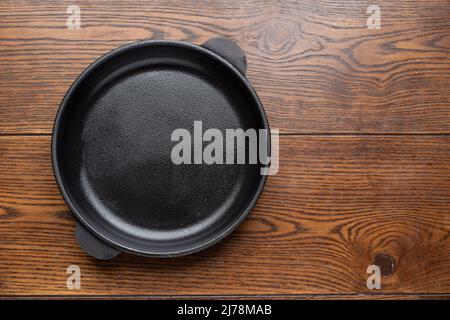 Leere Bratpfanne auf Holzhintergrund. Draufsicht. Stockfoto