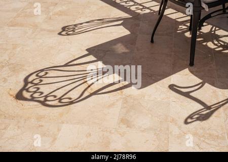 Schatten von leeren Stühlen in einem Café unter der heißen Sonne. Stockfoto