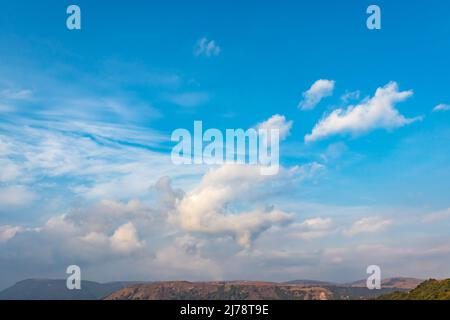 Strahlend blauer Himmel mit weißer Wolke über dem Berg am Morgen aus flachem Winkel Stockfoto