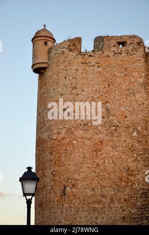 Alter Burgturm der Burg in Denia mit einer Straßenlampe davor unter sommerlichen Abendhimmel Stockfoto