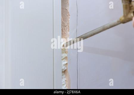 Installation der Türeinheit Reparaturman Montage Schaum der Türrahmen mit Polyurethanschaum Stockfoto