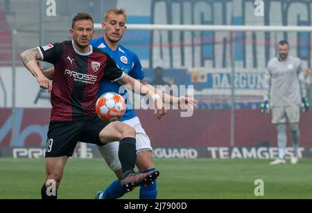 07. Mai 2022, Bayern, Ingolstadt: Fußball: 2. Bundesliga, FC Ingolstadt 04 - Hansa Rostock, Spieltag 33., Audi Sportpark. Vor der Bentley Baxter Bahn in Rostock kommt der Ingolstädter Marcel Gaus (l.) an den Ball. Foto: Stefan Puchner/dpa - WICHTIGER HINWEIS: Gemäß den Anforderungen der DFL Deutsche Fußball Liga und des DFB Deutscher Fußball-Bund ist es untersagt, im Stadion und/oder des Spiels aufgenommene Fotos in Form von Sequenzbildern und/oder videoähnlichen Fotoserien zu verwenden oder zu verwenden. Stockfoto