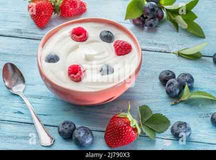 Keramikschale mit reinem Joghurt und Beeren auf dem Tisch. Leichte Sommerstimmung. Stockfoto